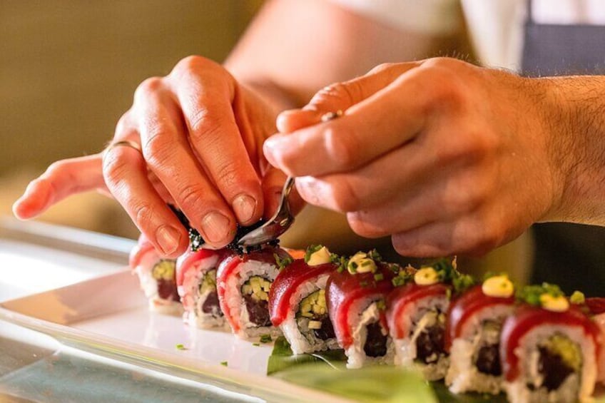 Una persona cortando rollos de sushi con un cuchillo. 3
