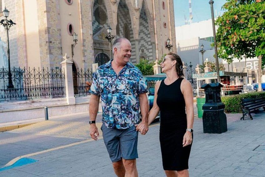 Een man en een vrouw wandelen over een verhard pad, met een historisch gebouw op de achtergrond. 5