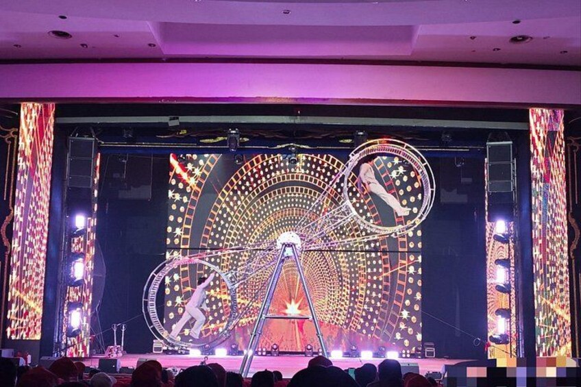 A stage with a performer, a large circular light structure, and a complex light display. 5