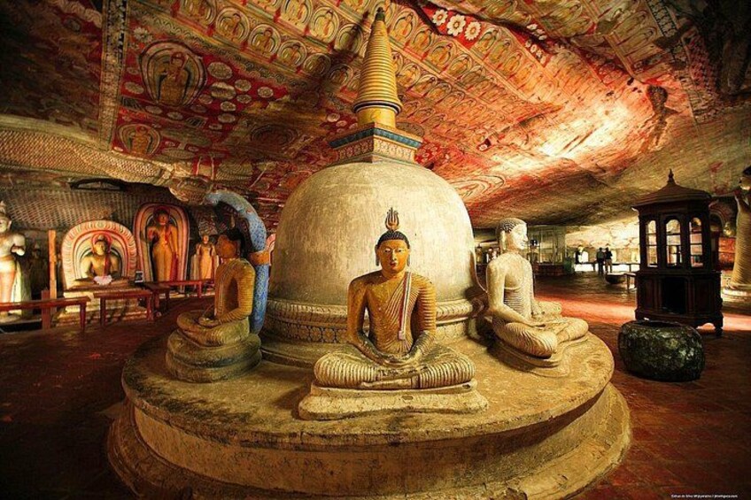 A large Buddha statue in a temple with intricate ceiling artwork and other statues. 2