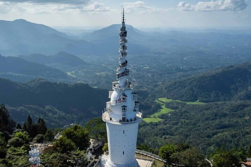 A white tower with multiple levels, surrounded by lush green hills and mountains. 1
