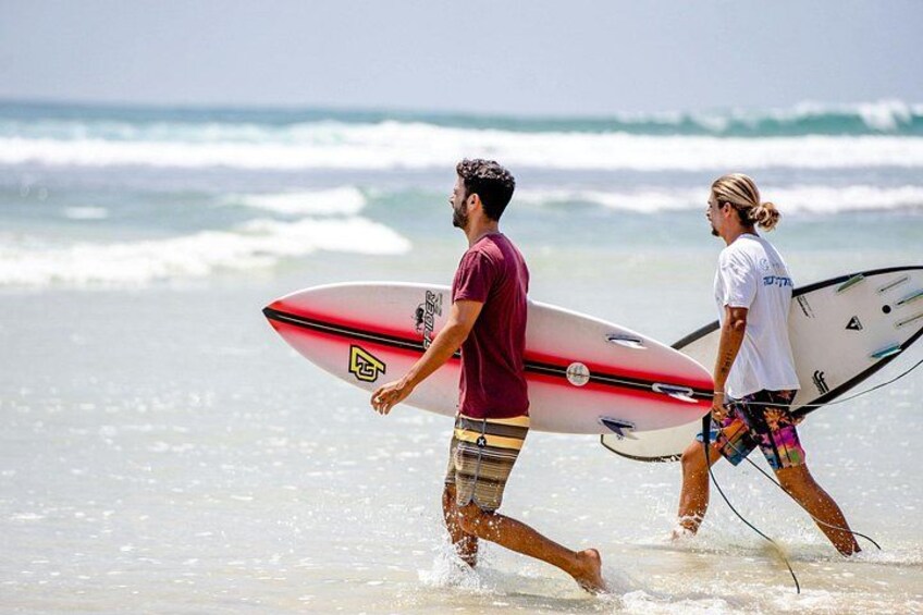 Two people walking on a beach with surfboards. 3
