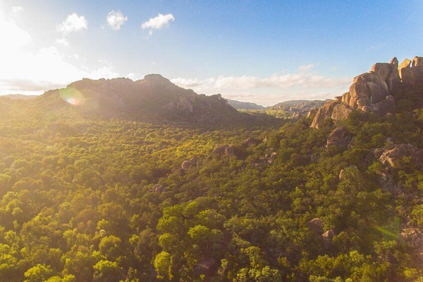 A mountainous landscape with dense green vegetation and rocky outcrops. 5