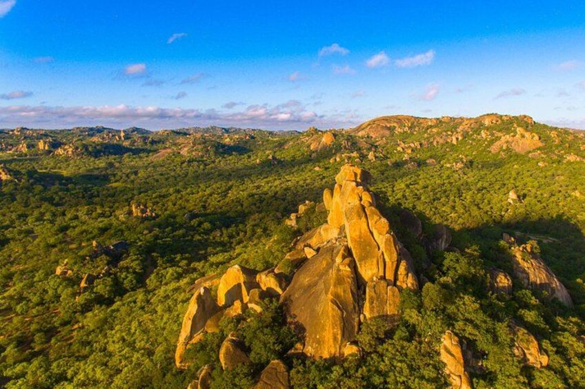 A mountainous landscape with prominent rock formations and dense green vegetation. 3