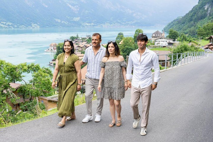 Eine Gruppe von Menschen geht auf einer Straße, im Hintergrund ein See und Berge. 4