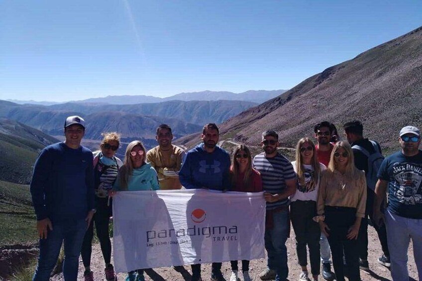 Eine Gruppe von Menschen steht auf einem Berg, mit einem Banner, auf dem 'paradigma travel' steht. 3