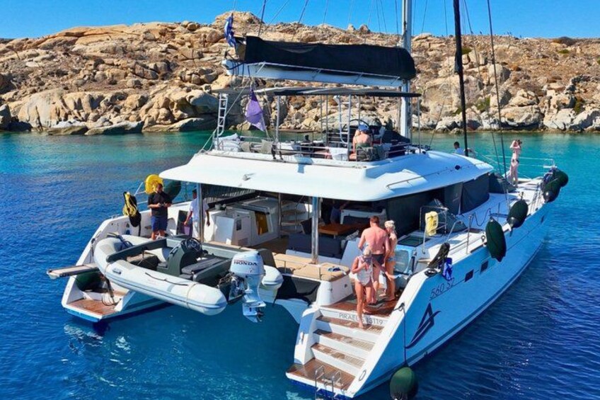 A white yacht docked at a rocky coastal area with clear blue water. 2