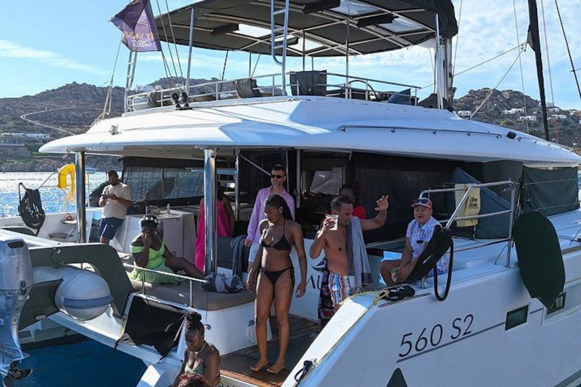 A sailboat with people on deck, a clear sky, and a body of water in the background. 5