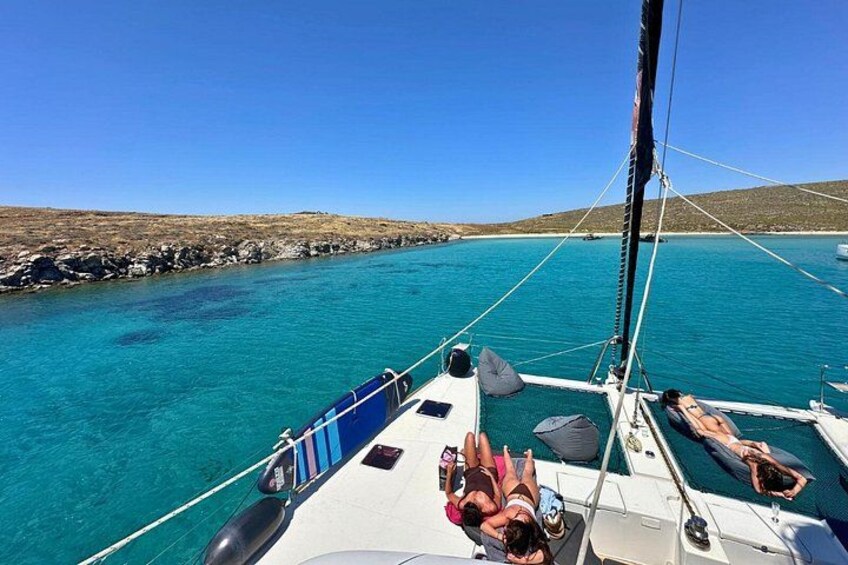 A sailboat on turquoise water with a rocky coastline in the background. 4