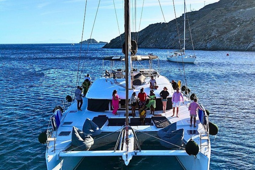 A sailboat with people on deck, calm sea, and distant rocky land. 3