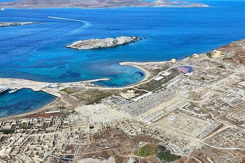 An aerial view of a coastal town with a marina, rocky outcrops, and a clear blue sea. 2