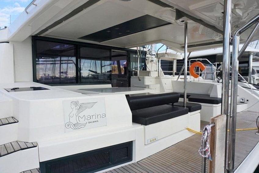 A yacht deck with a white lounge area, a logo, and a life ring. 3