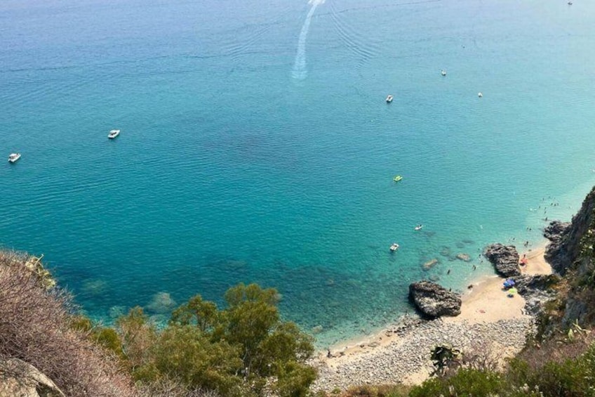 Un paysage côtier caractérisé par des eaux turquoise limpides, une côte rocheuse et une plage de sable. 4