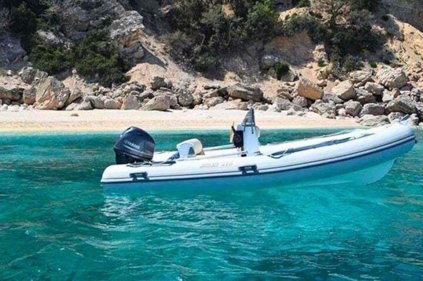 Un bateau à moteur sur une eau turquoise et limpide, avec une côte rocheuse en arrière-plan. 1