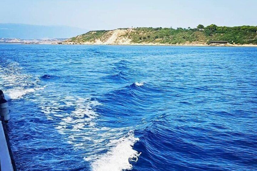 Une étendue d’eau avec des vagues, une côte lointaine bordée de végétation et un ciel dégagé. 2