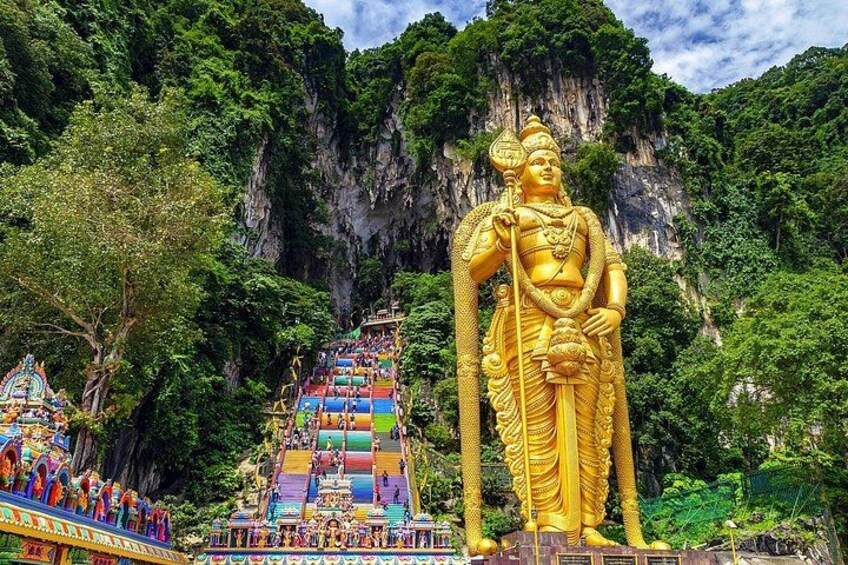 A large golden statue, a colorful temple, and a steep staircase against a mountainous backdrop. 3