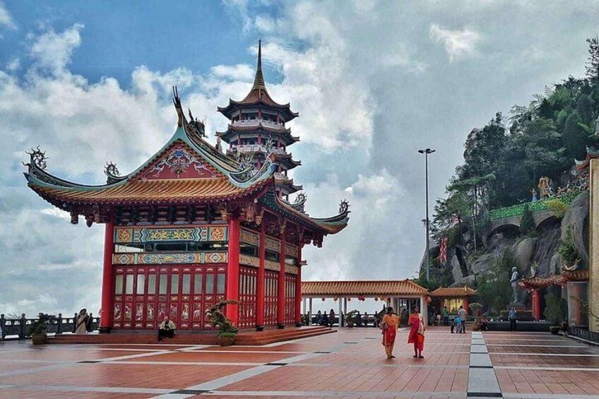 A traditional Chinese temple with ornate architecture, a tiled walkway, and a rocky hillside in the background. 5