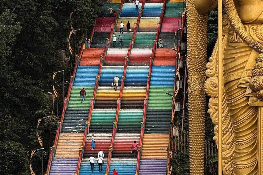 A colorful staircase with people walking and a large golden statue. 2