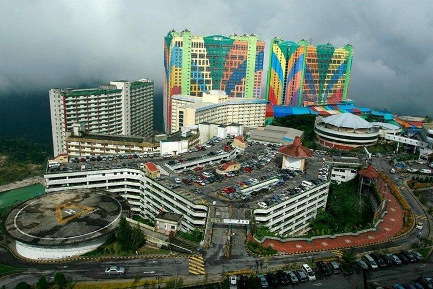 A large, colorful hotel complex with multiple buildings, a parking area, and a roundabout. 1