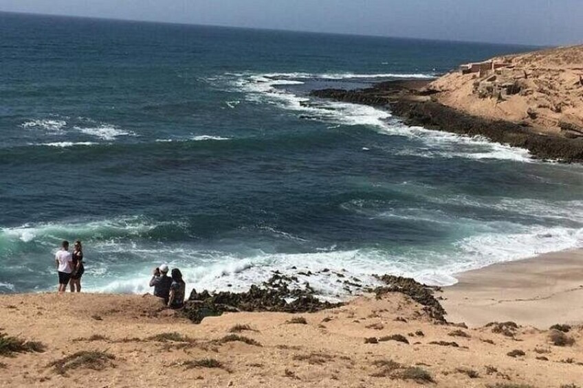 En strand med vågor som bryter mot land, ett sandområde och klippiga utskjutande partier. 5