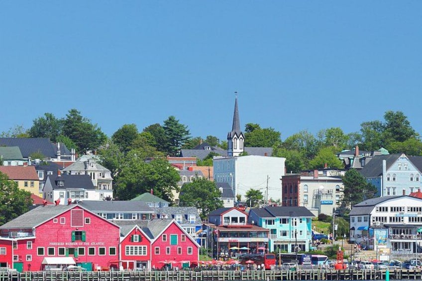 A coastal town with colorful buildings, a church steeple, and a dock with boats. 1