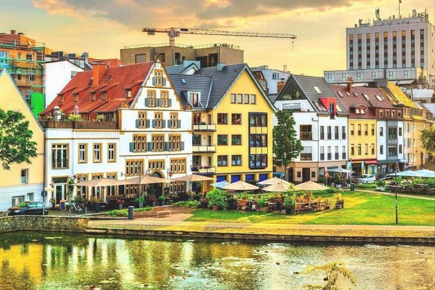 A riverside town with colorful buildings, a grassy area, and a calm water body. 1
