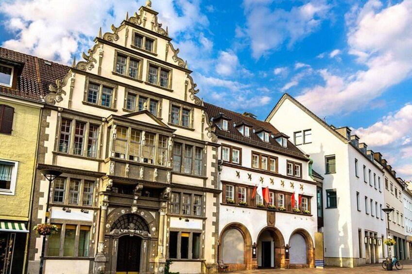 A historic building with ornate architecture, a street with a bicycle, and a clear blue sky. 2