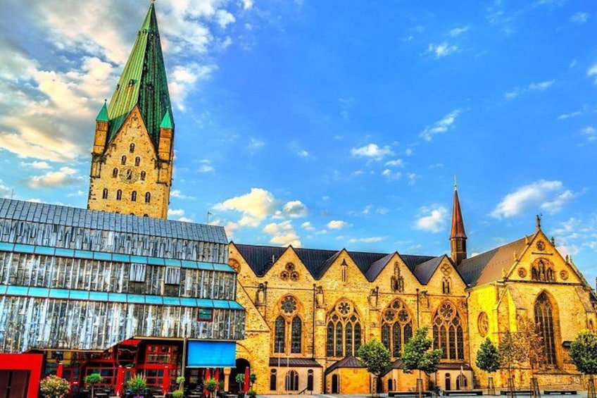 A historic church with a tall tower and a modern building with a blue facade. 5