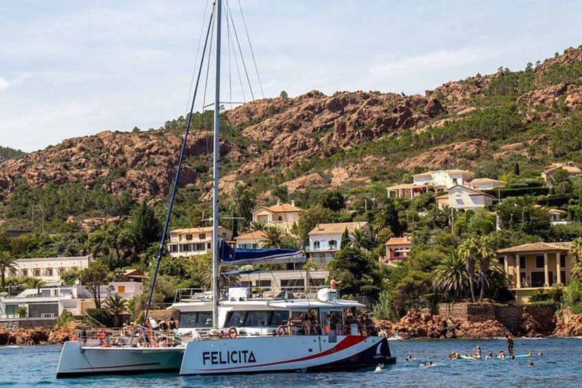 A sailboat named FELICITA on calm waters, with a rocky hillside and houses in the background. 4