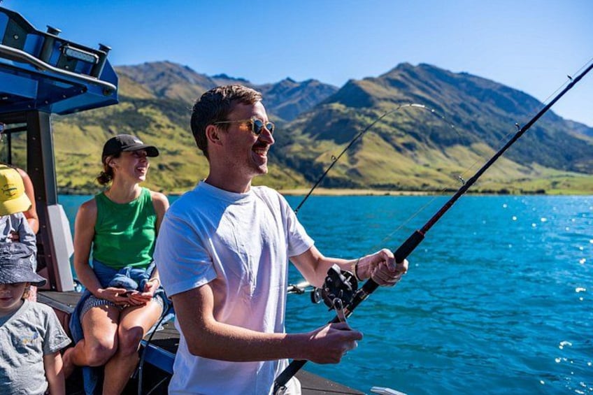 A person fishing on a boat with a mountainous landscape in the background. 4