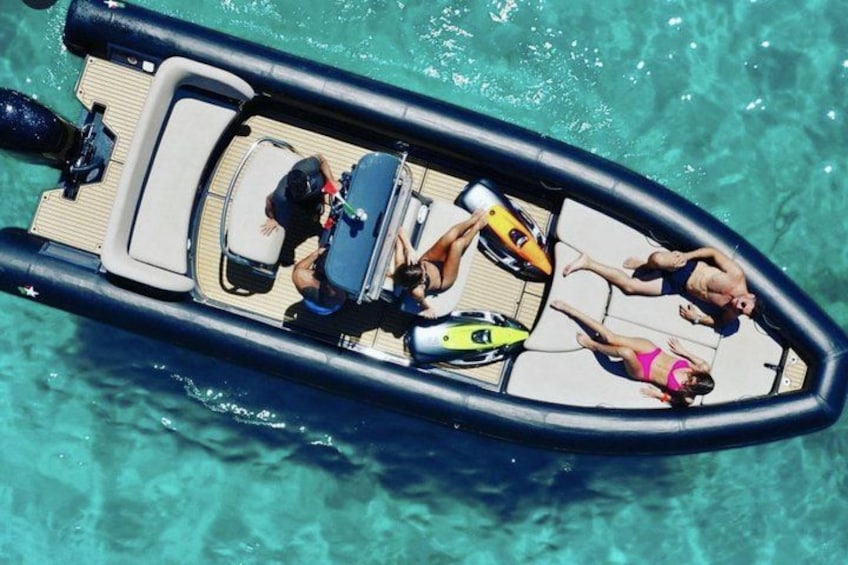 A small inflatable boat with people sunbathing on a wooden deck. 1