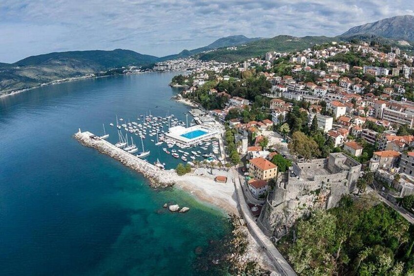 A coastal town with a marina, historic buildings, and a mountainous backdrop. 4