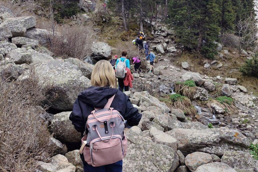 Hikers on a rocky trail with large boulders and sparse vegetation. 3