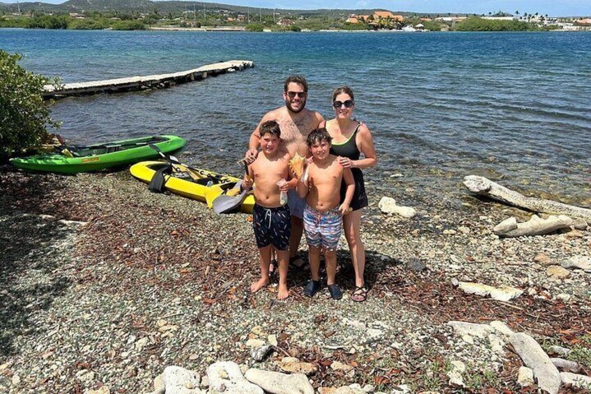 A family by a lake with kayaks and a rocky shore. 4
