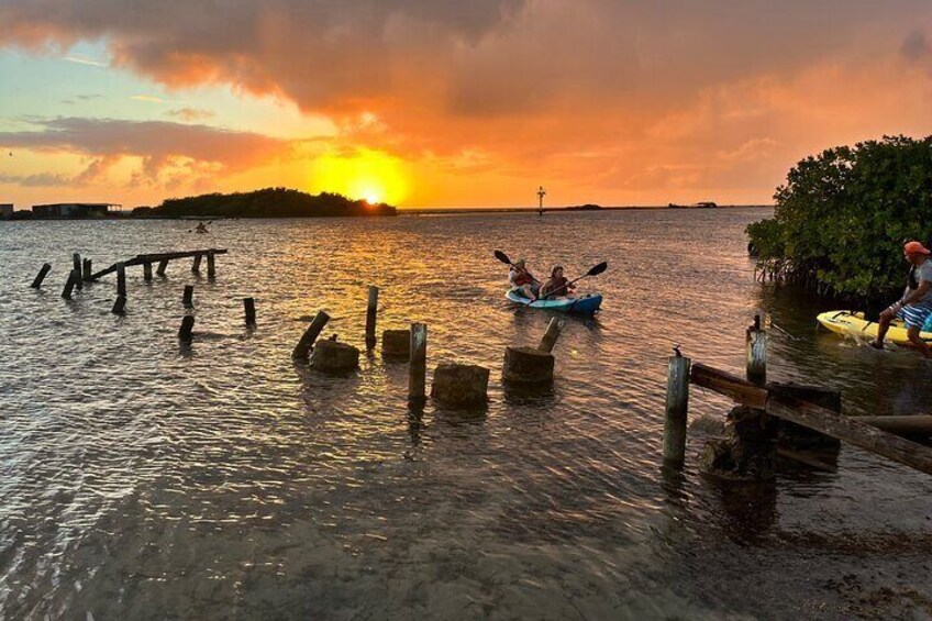 A sunset over water with a dock and kayaks. 3