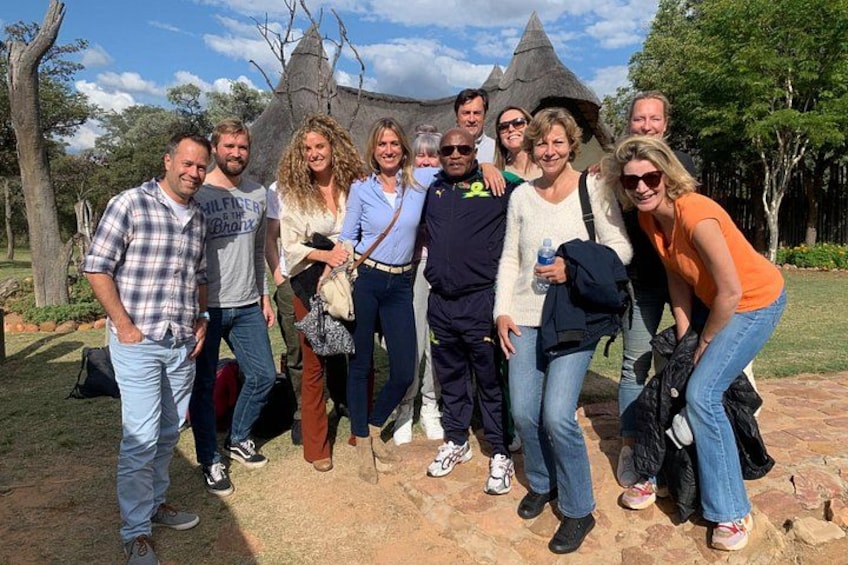 Un grupo de personas posando frente a una estructura de piedra con techo puntiagudo. 5