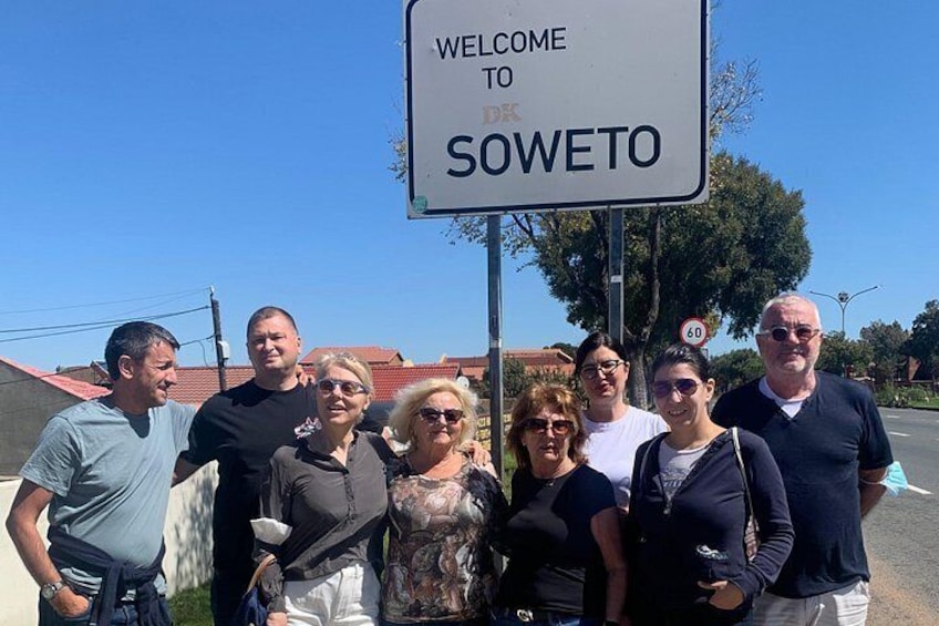 Un grupo de personas frente a un letrero que dice 'WELCOME TO SOWETO'. 1