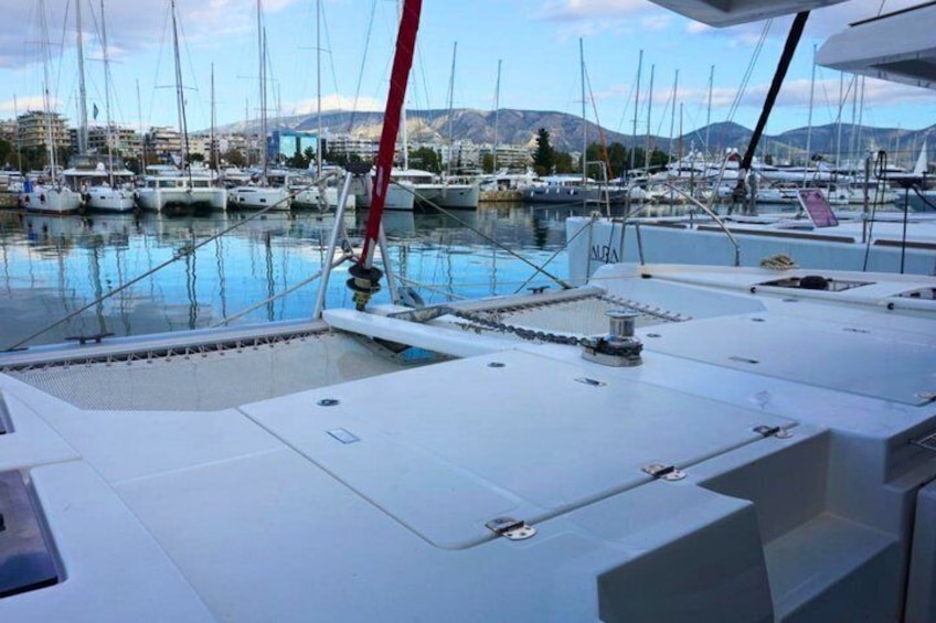 Ein Yachthafen mit mehreren Segelbooten, bewölkter Himmel und Bergen im Hintergrund. 2