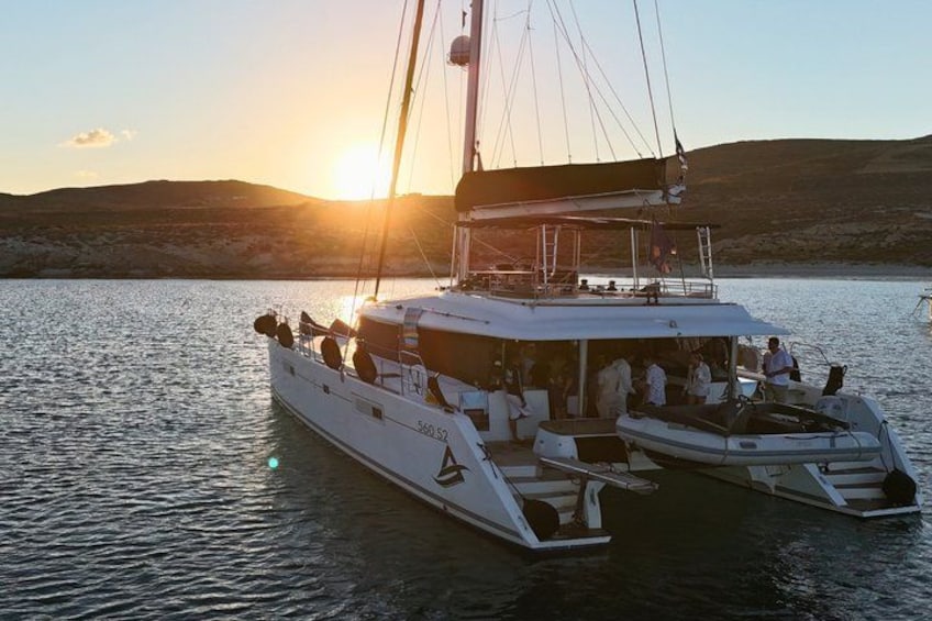 Een witte catamaran met nummer 56052 vaart over kalm water tijdens de zonsondergang. 4