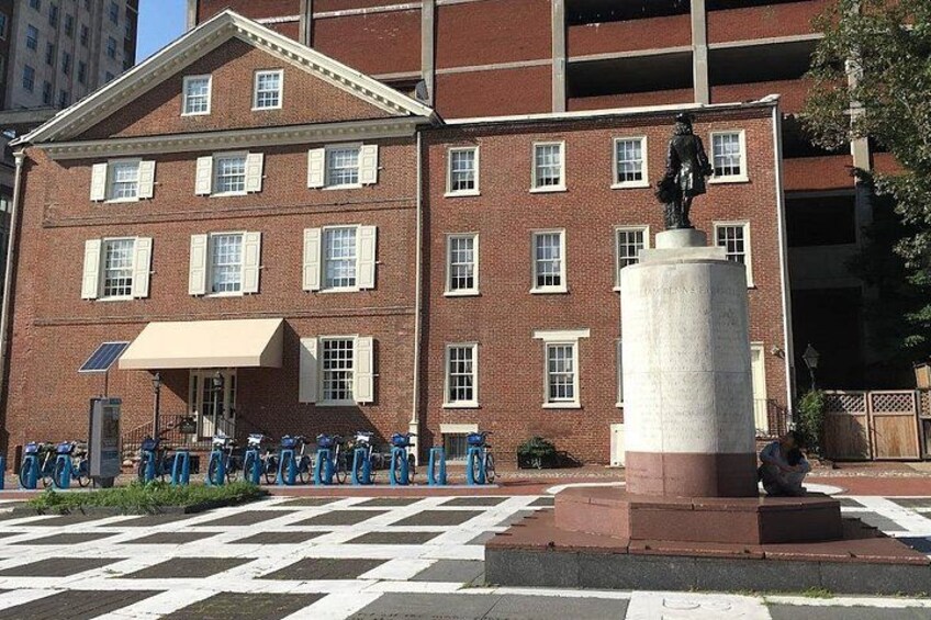A red brick building with a statue on a pedestal, a bicycle parking area, and a crosswalk. 5