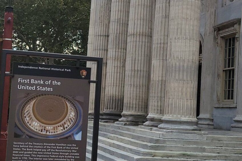 A historical building with a sign for Independence National Historical Park and a plaque about the First Bank of the United States. 1