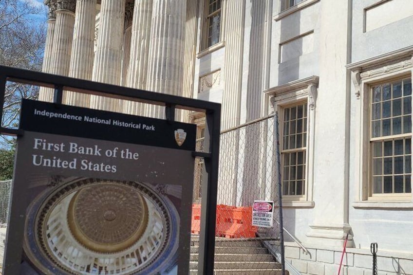 En historisk byggnad med en skylt som visar att det är platsen för First Bank of the United States och Independence National Historical Park. 4