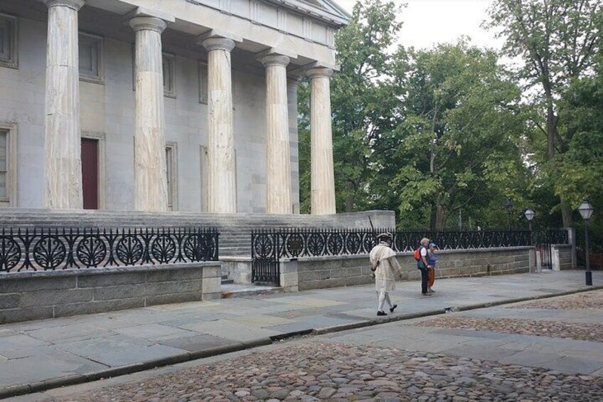 A classical building with columns, a stone pathway, and a metal fence. 2