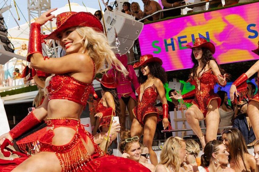 A group of people in red costumes performing on a stage with a large screen displaying text in the background. 2