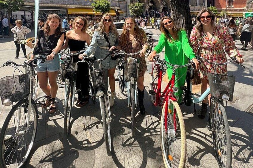 A group of people on bicycles in an urban setting with trees and buildings in the background. 3