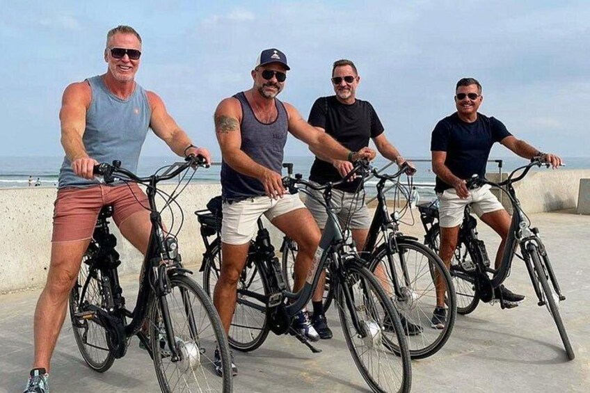 Four people on bicycles by a beach. 4