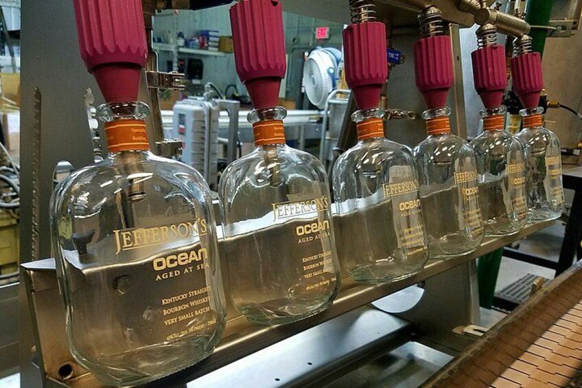 Bottles of Jefferson's Ocean aged whiskey on a conveyor belt in a factory setting. 2