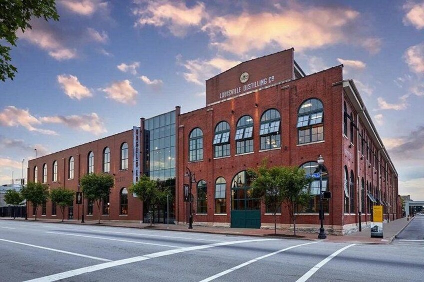 A red brick building with large windows and a sign that reads 'Louisville Distilling Co.' 1