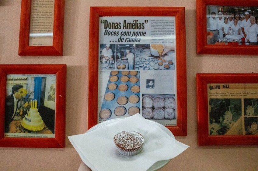 En vägg med inramade bilder, inklusive en inramad artikel om ”Donas Amelias” och ett inramat foto av en grupp människor. 2