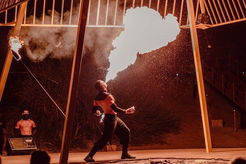 A person performing an act with a flaming object, a metal structure, and a smoke effect. 2